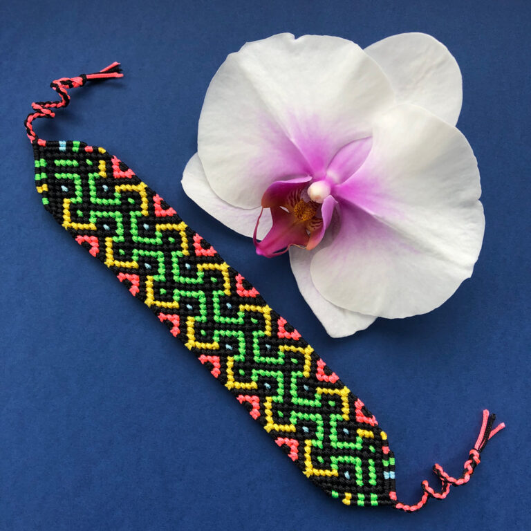 Friendship bracelet wypleciona z nitek w kolorach: czarnym, jasnozielonym, żółtym, jaskraworóżowym i jasnoniebieskim